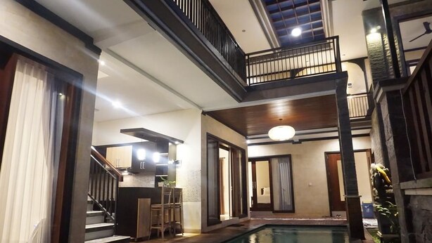A multi-level indoor pool area with a staircase, a bar area, and a seating space.