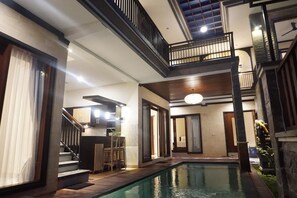 Un área de piscina interior con varios niveles, una escalera, zona de bar y un espacio para sentarse.