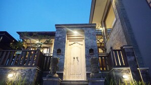 A building entrance with a wooden door, stone columns, and a balcony with railings.