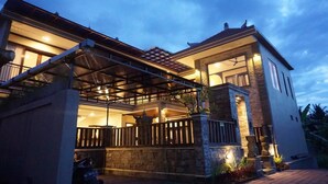 A modern house with a covered patio, stone walls, and a well-lit entrance.