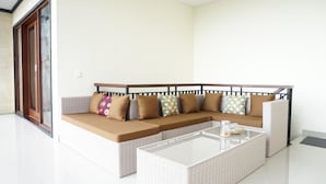 A modern living room with a sectional sofa, a glass coffee table, and a sliding glass door.