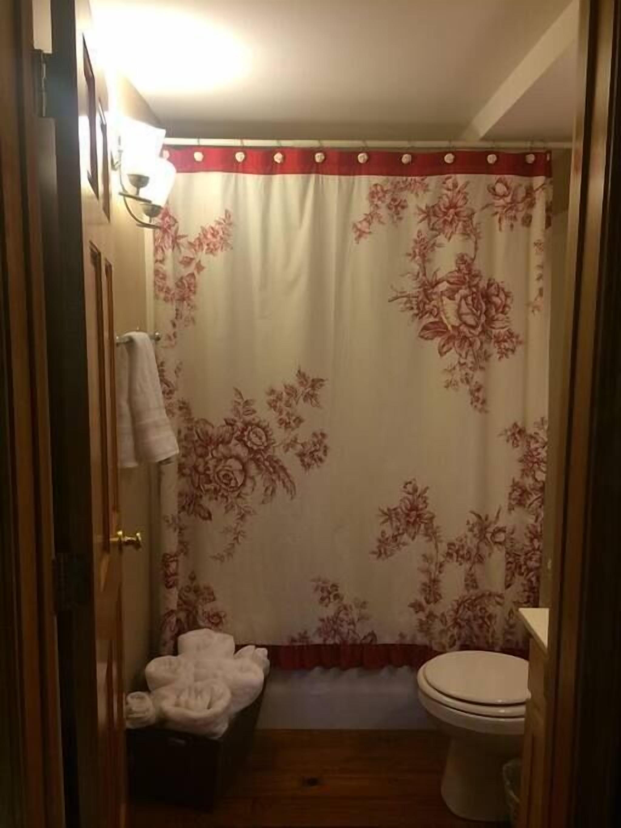 Un baño con cortina de ducha, inodoro y un banco con toallas.
