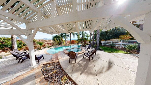 Un espacio al aire libre techado con piscina, mobiliario y vistas al paisaje.