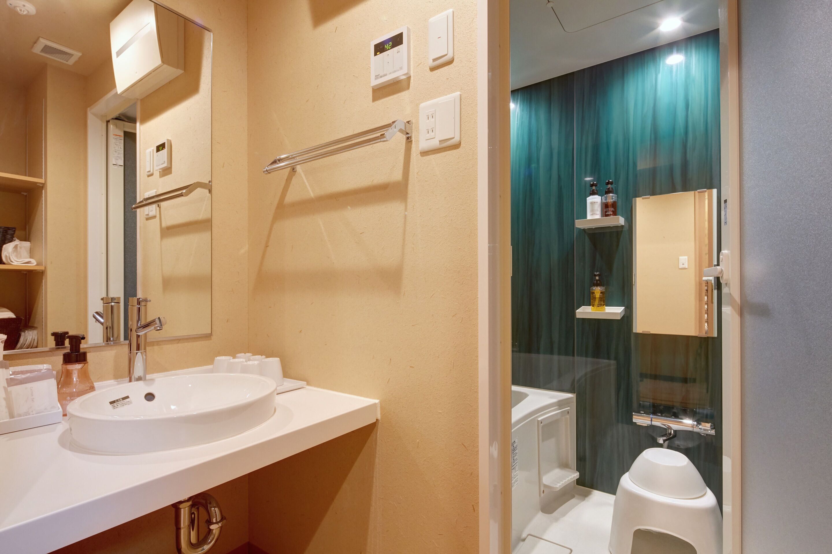 A modern bathroom with a white sink, mirror, and a glass-enclosed shower area.
