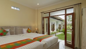 A bedroom with two beds, a wooden headboard, and a view of a garden through a sliding glass door. - Pondok Ayu Shanti (Ubud)