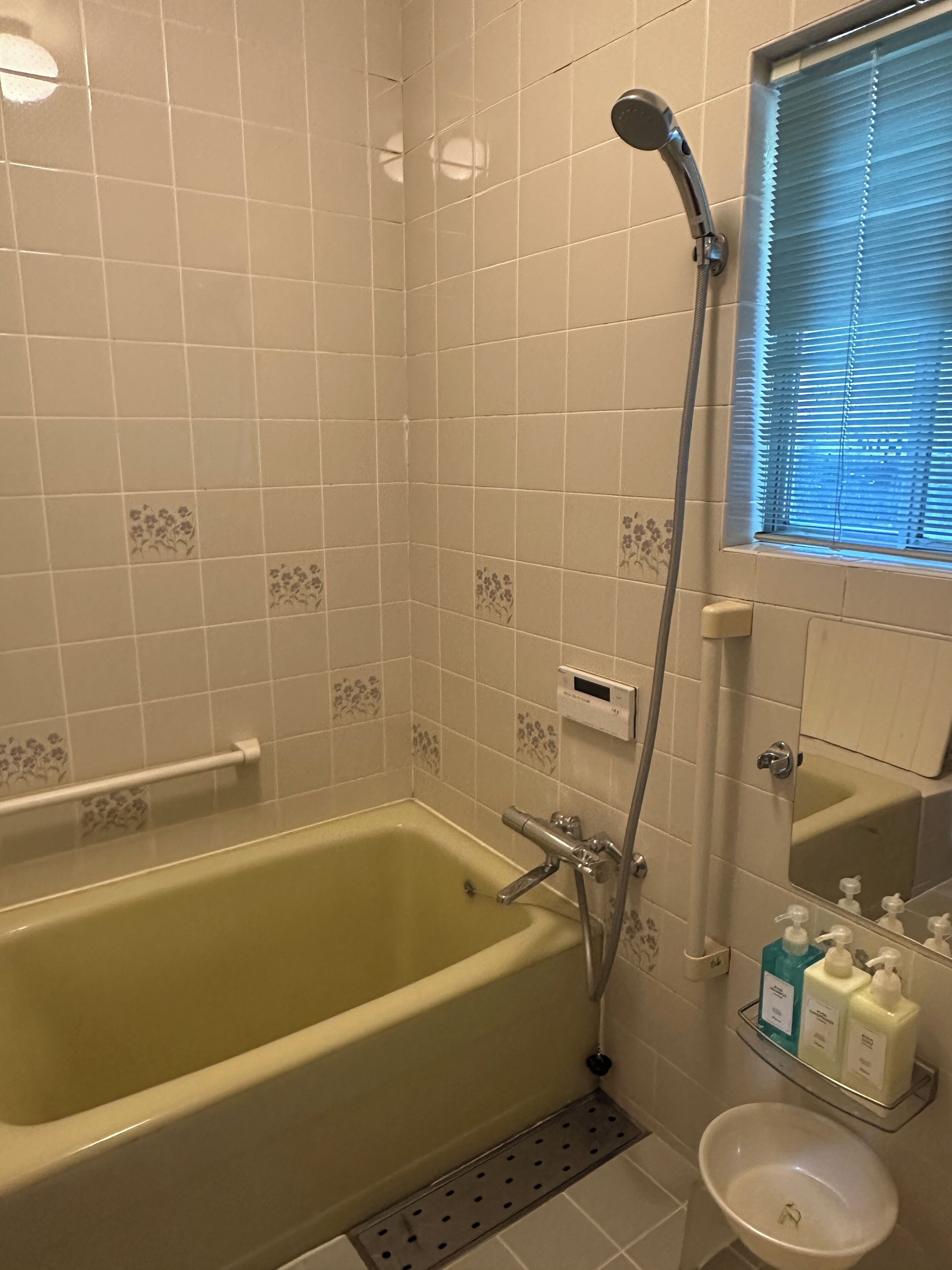 A bathroom with a bathtub, a shower, a sink, and a window with blinds.