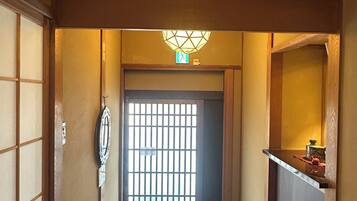 A hallway with a traditional Japanese-style door, a tiled floor, and a small trash bin.