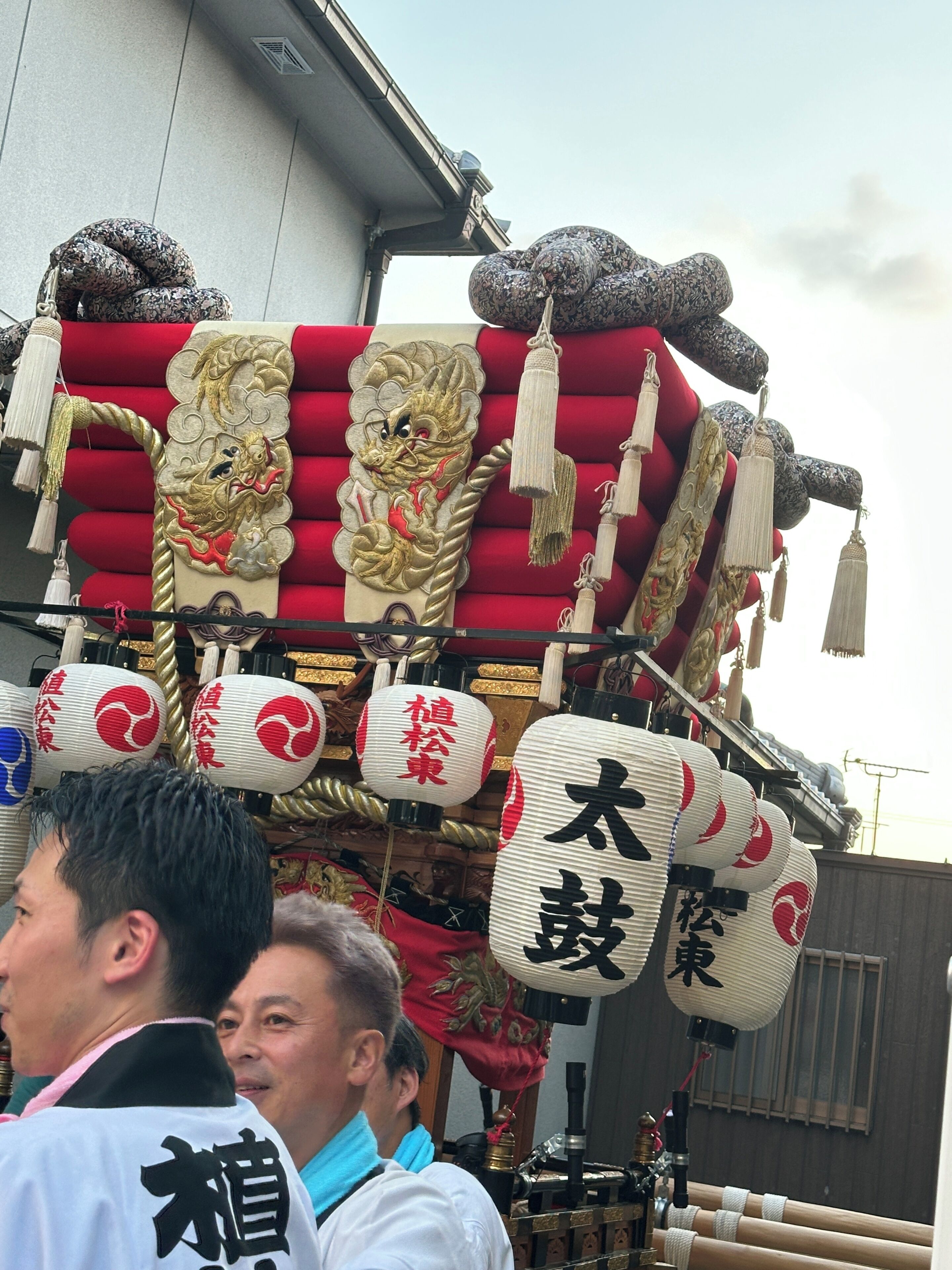 A traditional Japanese building with a red and gold ornate structure, possibly a shrine or temple, with white lanterns and Chinese characters.