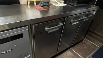 Cocina de acero inoxidable con horno integrado, microondas y lavamanos.