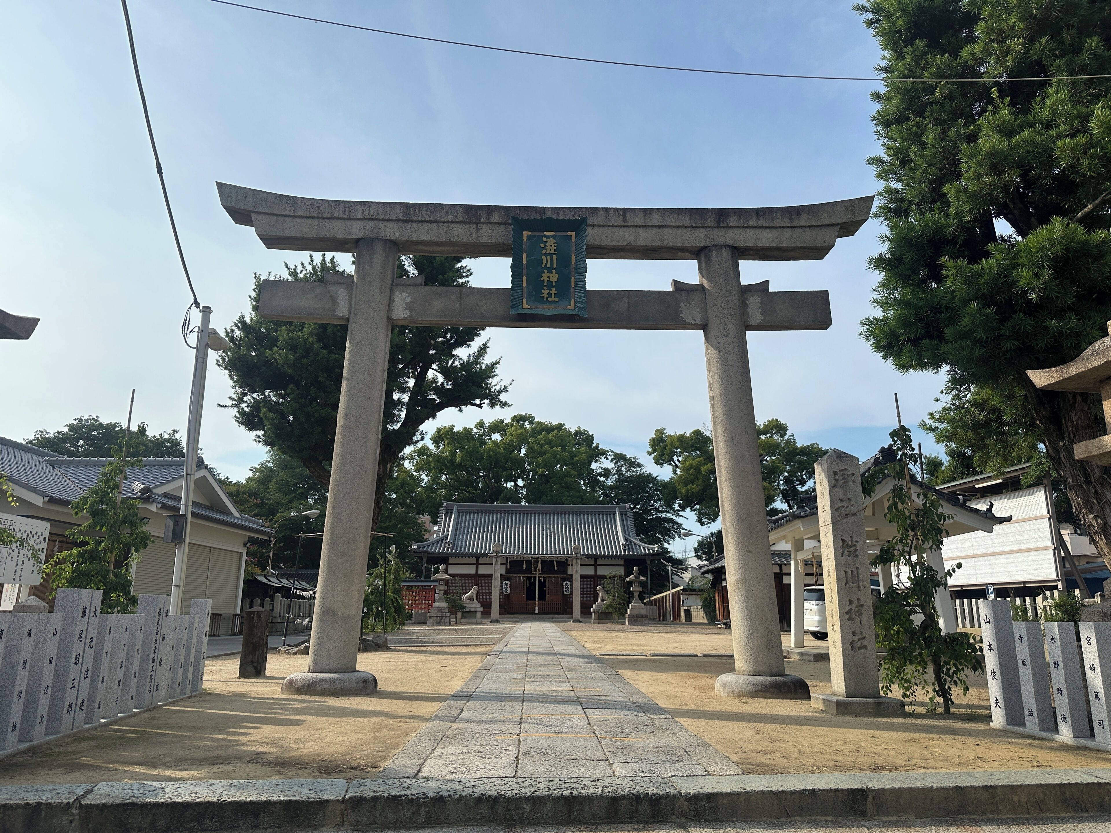 Un portail torii japonais traditionnel, menant à un temple dont le toit est recouvert de tuiles.