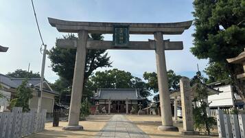 Un portail torii japonais traditionnel, menant à un temple dont le toit est recouvert de tuiles.