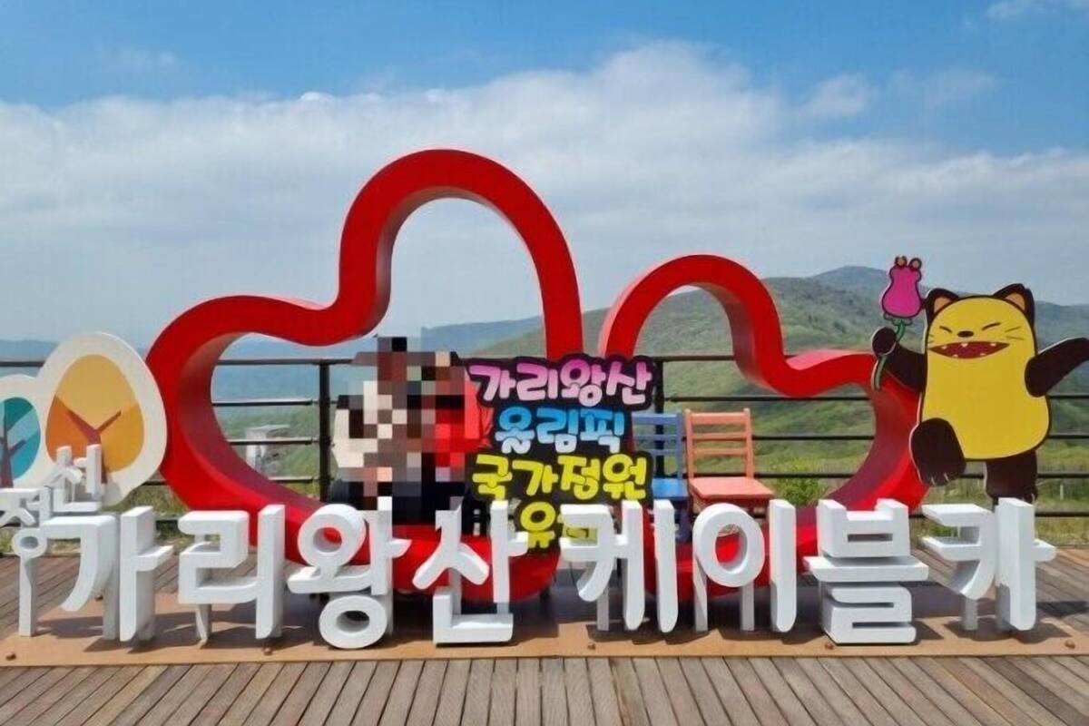 A sign with Korean text and a cartoon character, set against a scenic backdrop.
