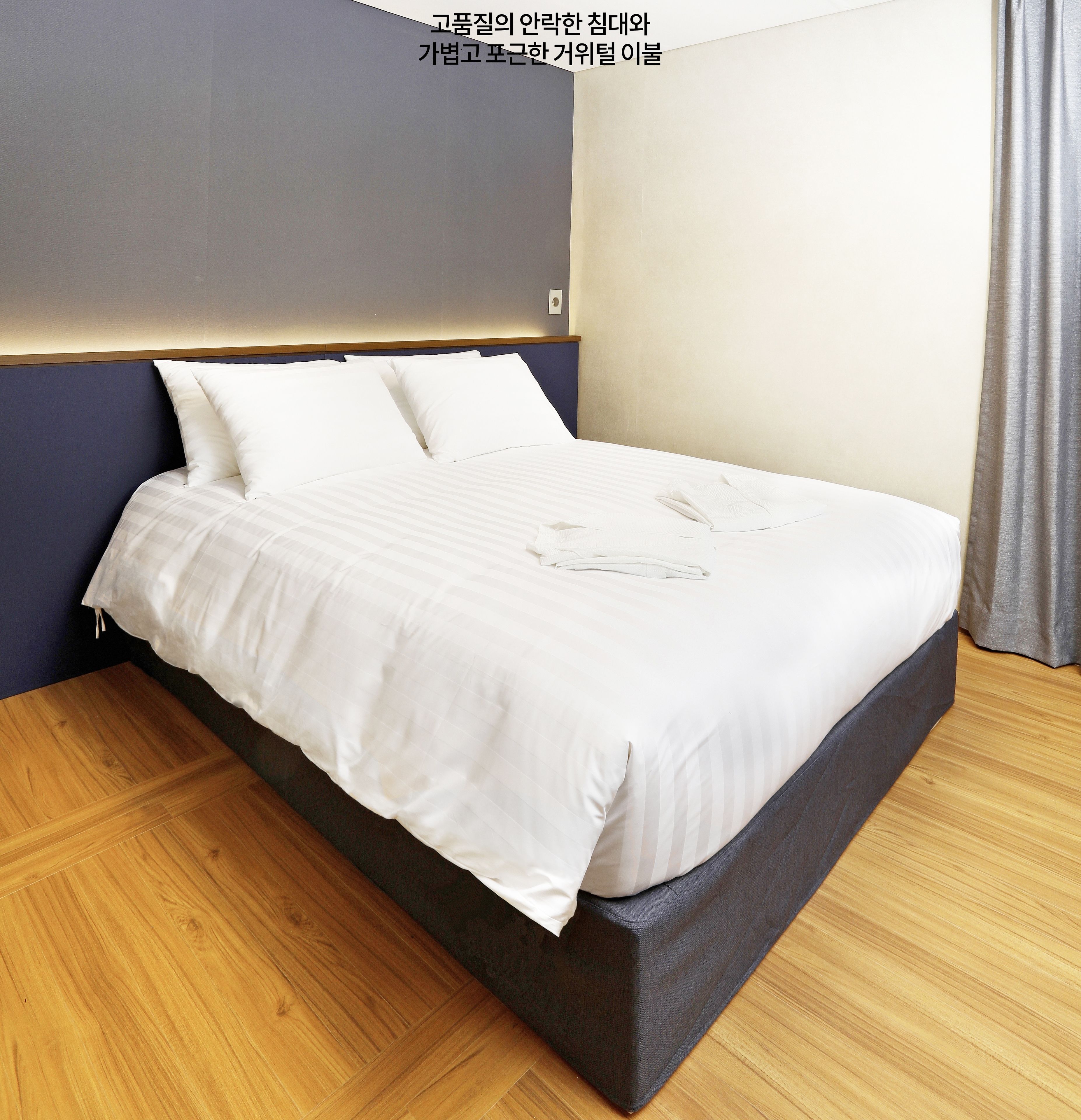 Ein modernes Schlafzimmer mit einem großen Bett, einem dunklen Kopfteil und Holzböden.