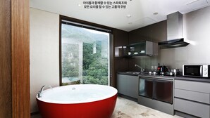 A modern bathroom with a large red bathtub and a view of a mountainous landscape through a large window. - Pine Forest (Jeongseon)