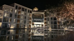 A multi-story hotel with a central atrium, balconies, and a reflective pool. - Pine Forest (Jeongseon)