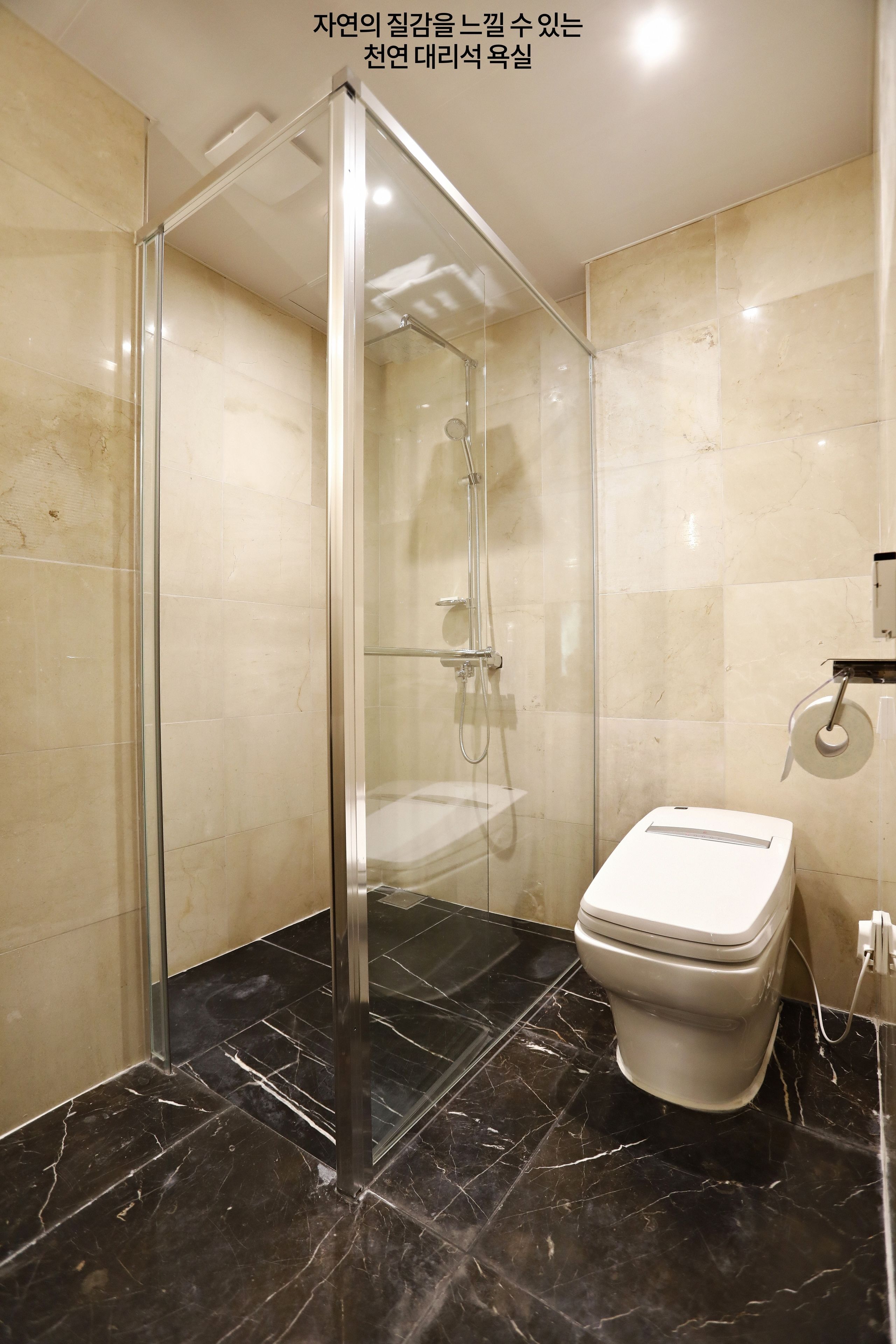 A modern bathroom with a glass-enclosed shower, a toilet, and a marble floor.