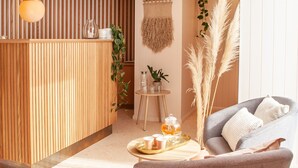 Una sala de estar moderna con un mostrador de recepción de madera, un sillón gris y una pequeña mesa redonda con una bandeja de objetos.
