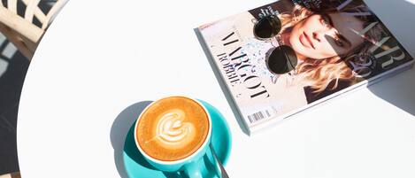 Una taula amb una revista, una tassa de cafè i una cadira.