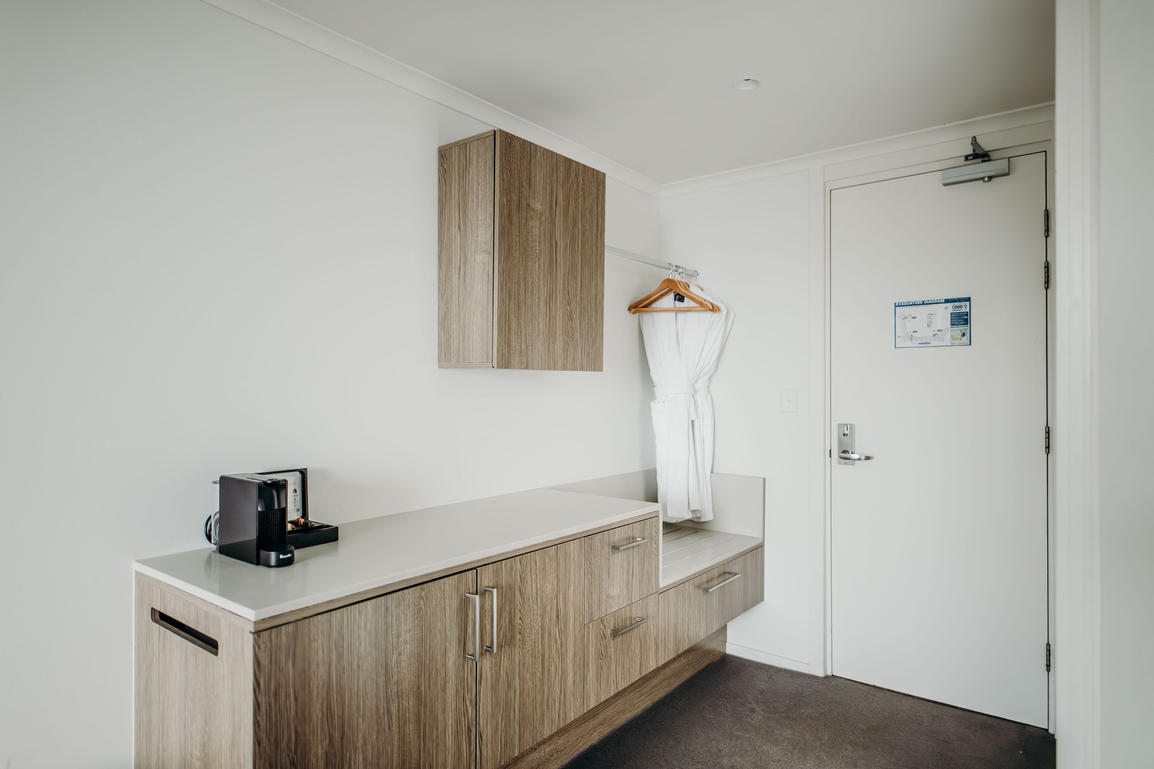 Une salle de bain moderne avec un meuble-lavabo en bois, un porte-serviettes et une machine à café.