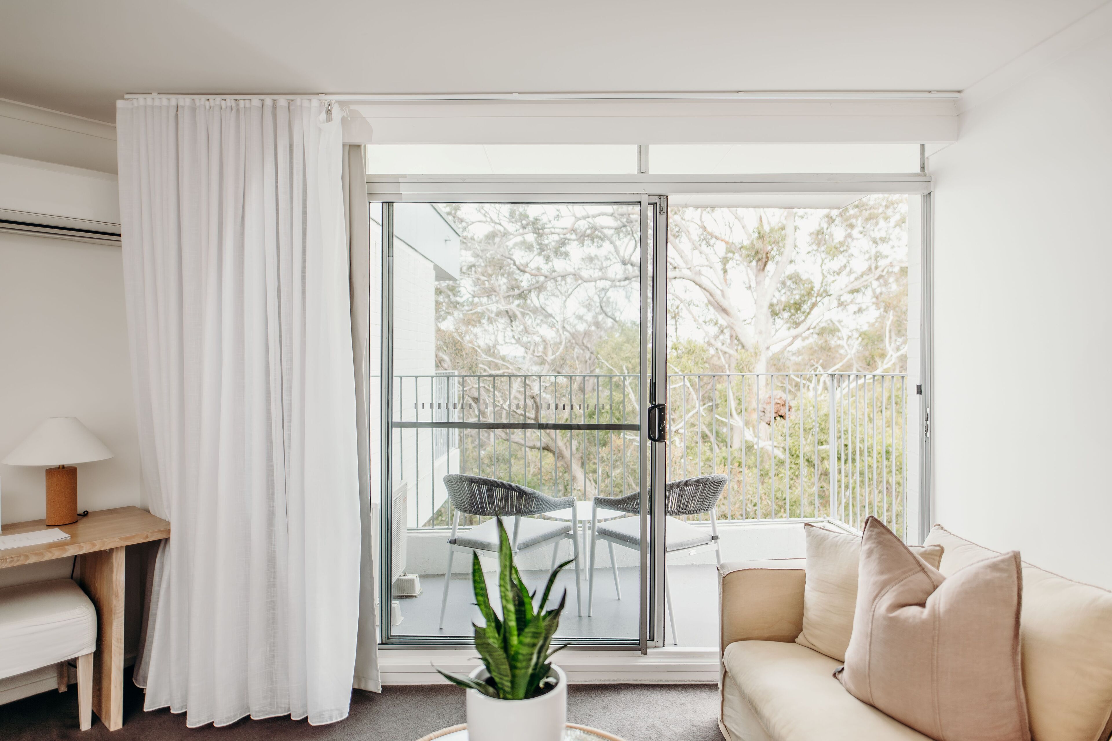 A modern room with a sliding glass door leading to an outdoor area with a table and chairs.