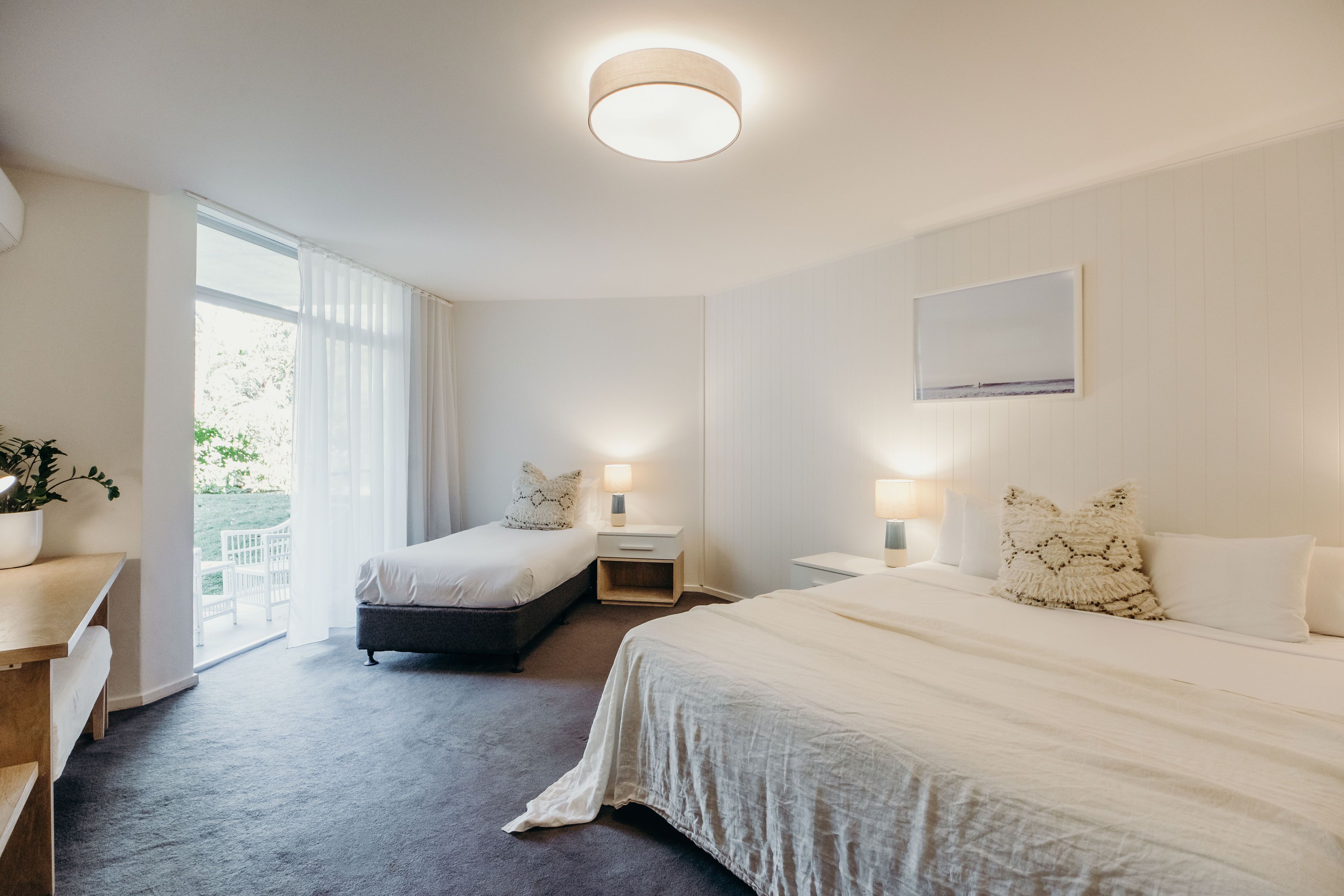 Een moderne hotelkamer met een groot bed, een kleiner bed, een bureau en uitzicht op de omgeving.