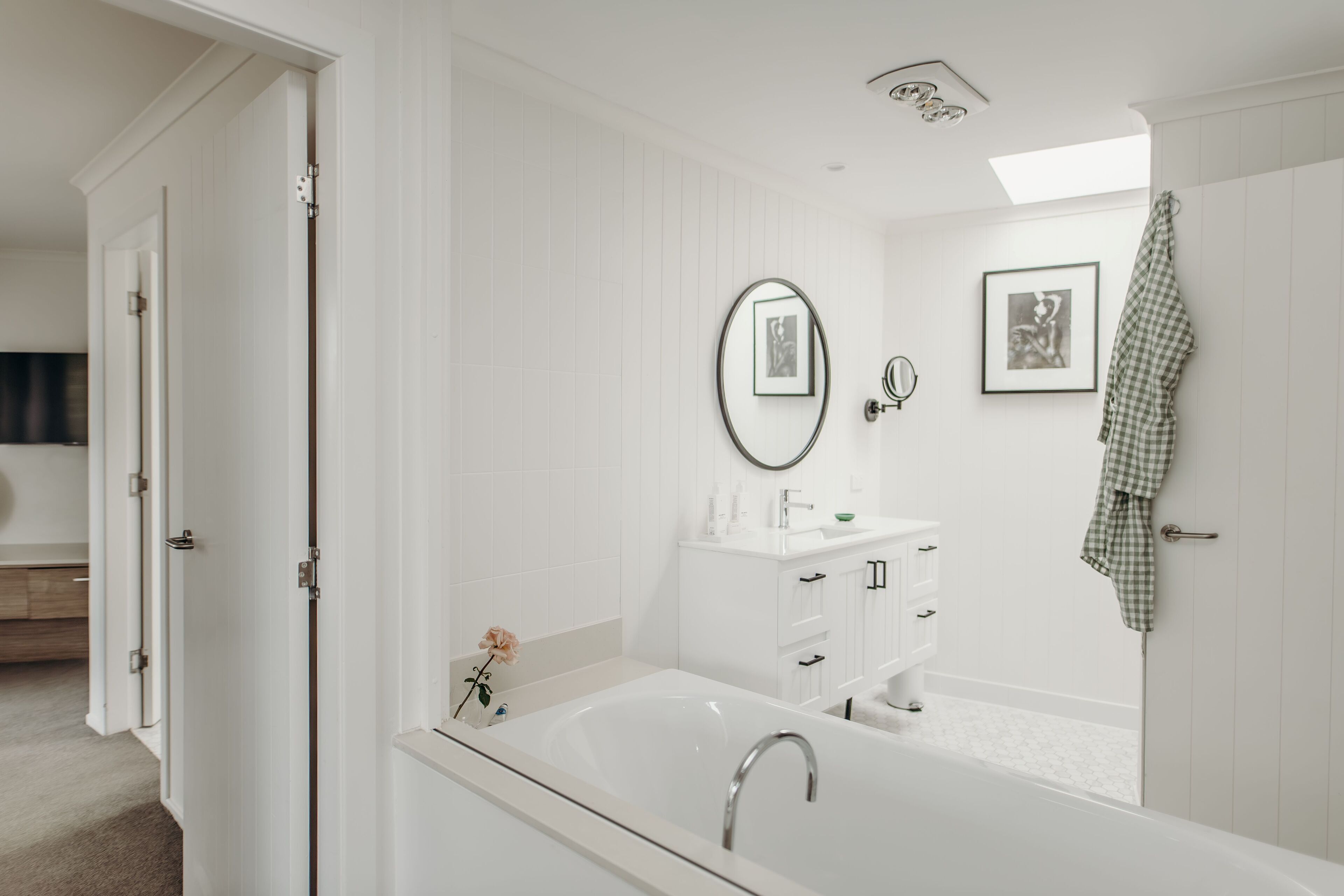 A modern bathroom with a freestanding bathtub, a vanity with a mirror, and a framed picture on the wall.