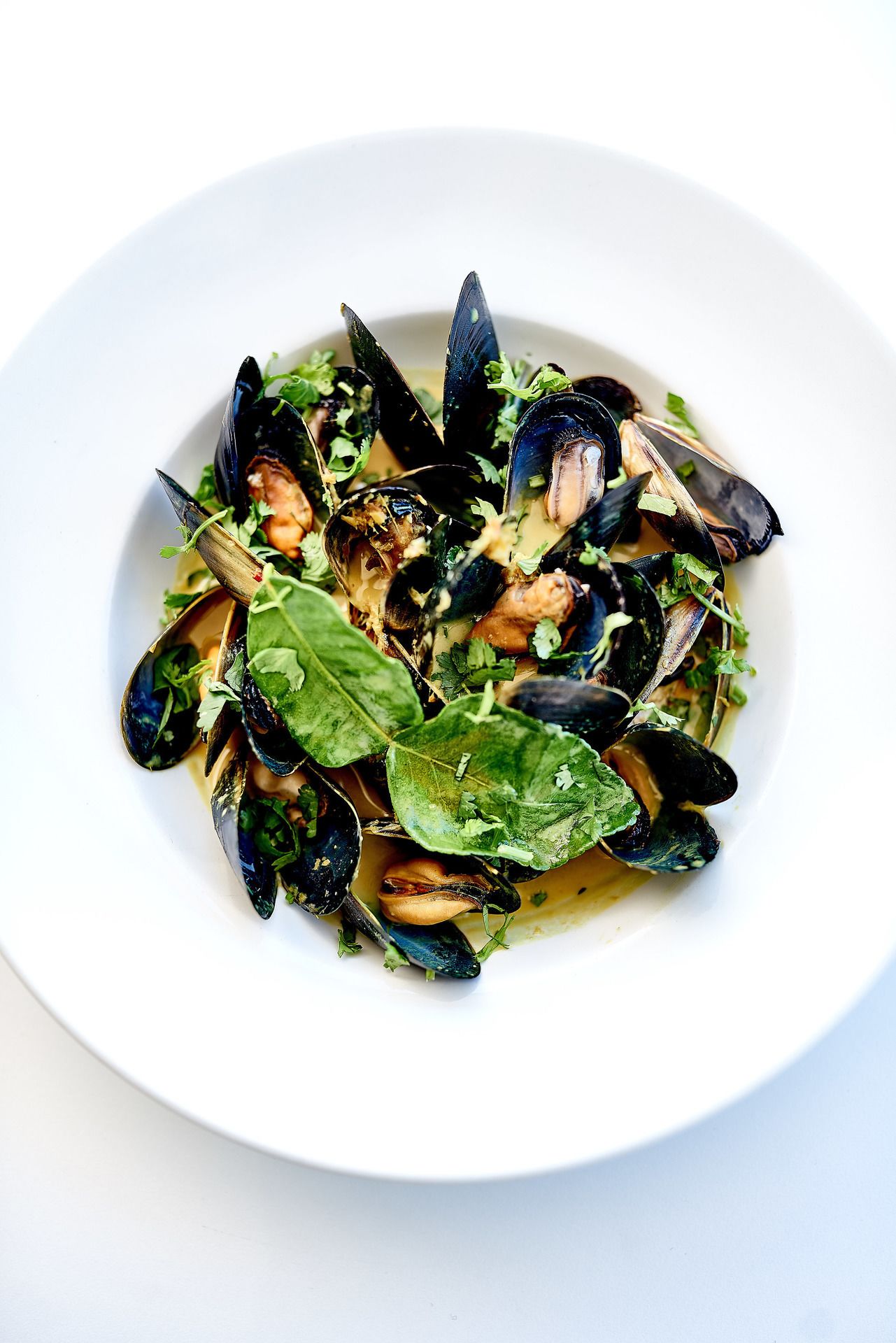Un plato de mejillones con vegetales y hierbas.