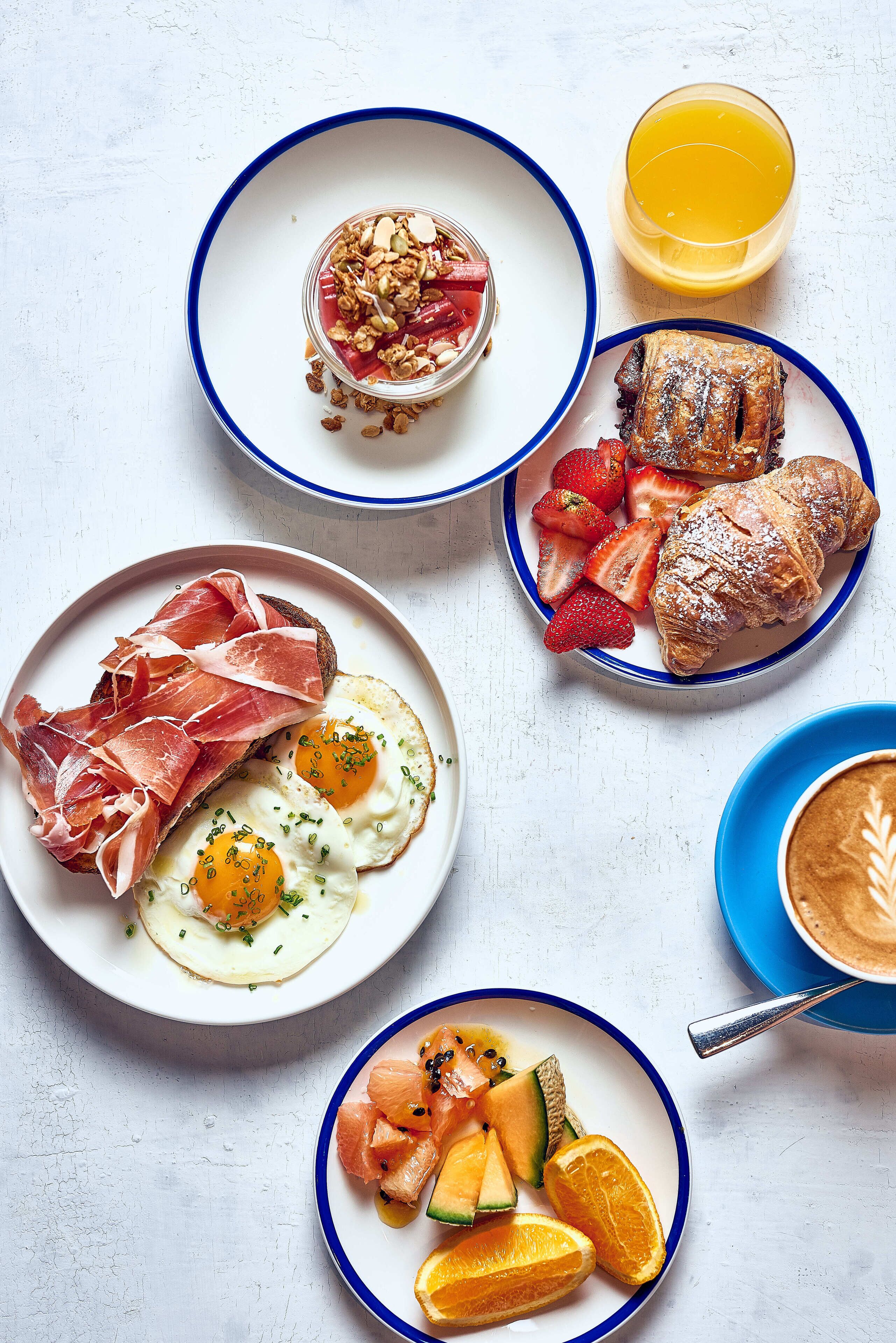 A breakfast setting with various dishes including eggs, pastries, and fruits.