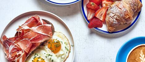 A breakfast setting with various dishes including eggs, pastries, and fruits.