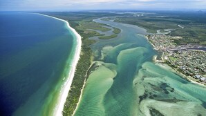 Luftaufnahme einer Küstenlandschaft mit Strand, Fluss und einer Stadt.