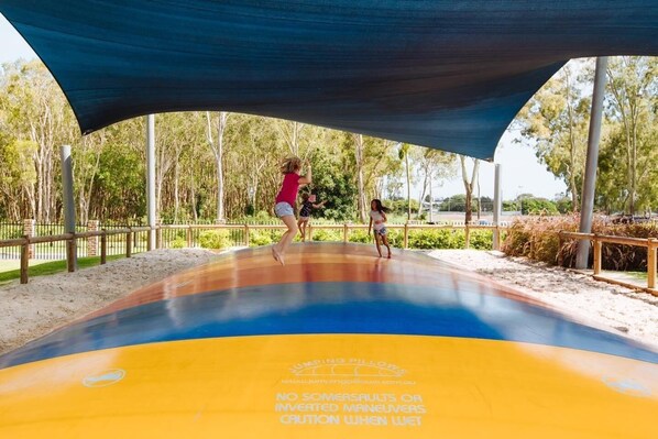 A trampoline park with a shaded area and a warning sign.