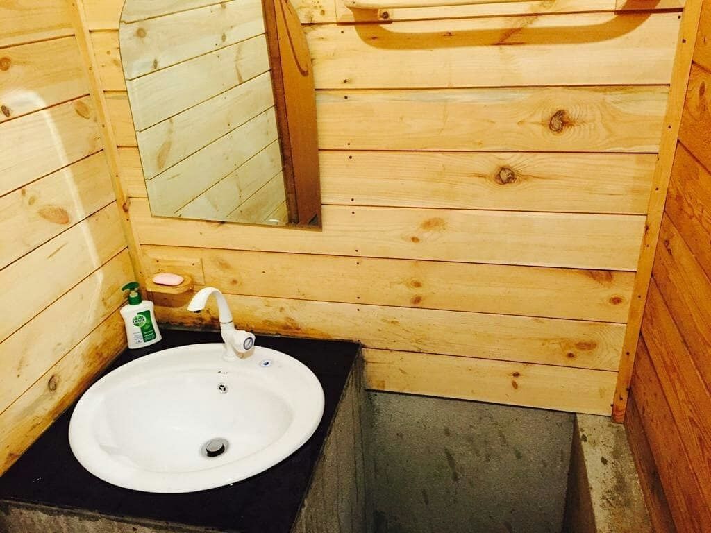 A wooden cabin bathroom with a white sink, a mirror, and a soap dispenser.