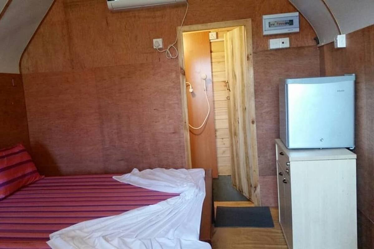 Une petite pièce confortable, avec un lit, une porte en bois, un petit meuble et un téléviseur.