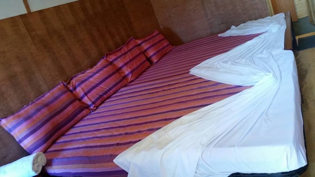 A bed with striped bedding, pillows, and a white sheet.