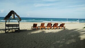 Une plage avec une structure en bois et des chaises longues donnant sur l’océan.