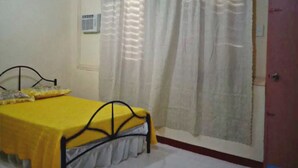 Une chambre à coucher avec un lit, une fenêtre avec des rideaux, une porte et un appareil de climatisation.