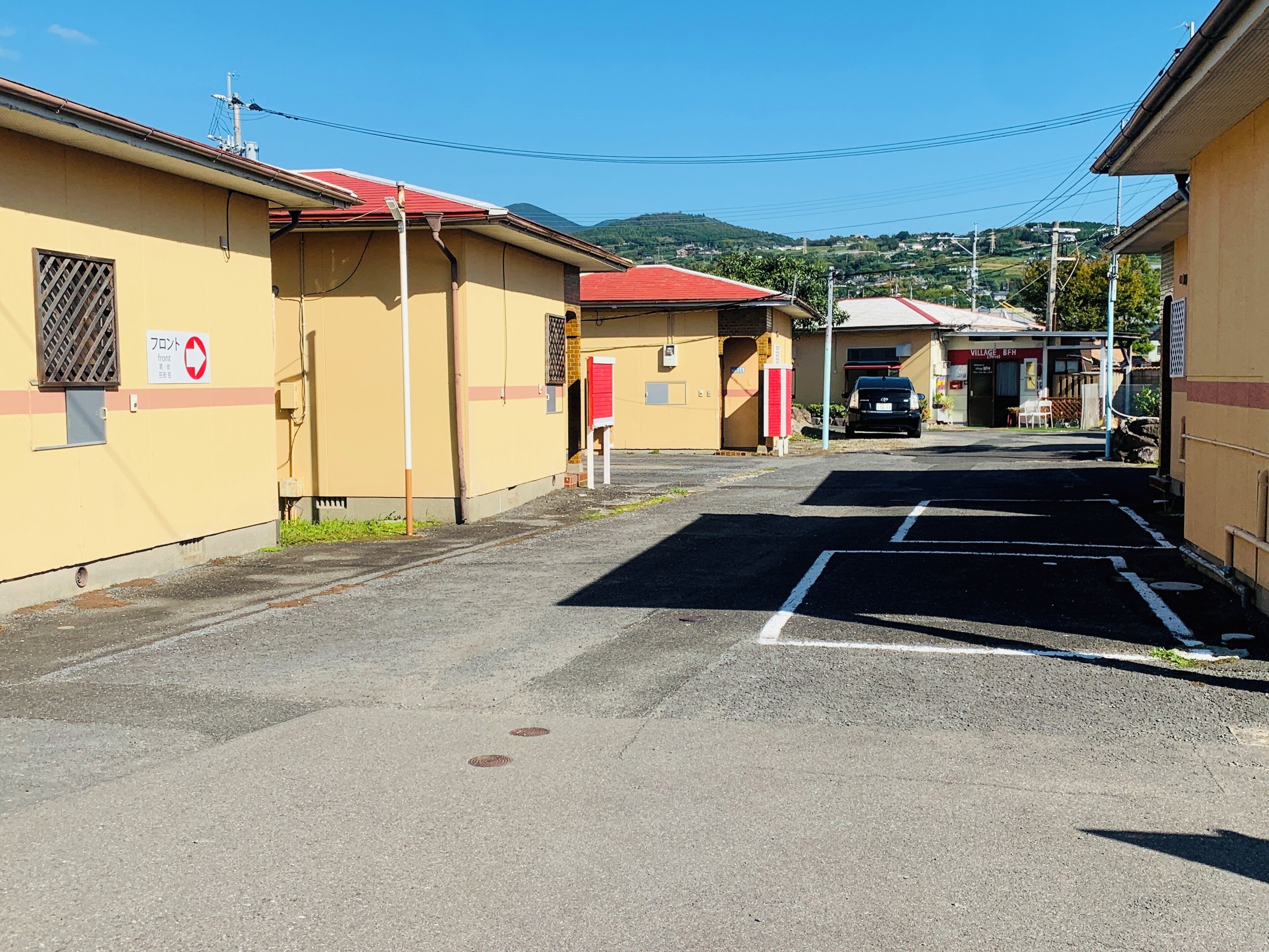 A parking lot with a building on the left and a sign that reads "VILLAGE BPH".