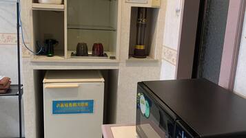 Une chambre d’hôtel équipée d’un mini-bar, d’un réfrigérateur, d’un four à micro-ondes et d’un petit meuble contenant une bouilloire et des tasses.