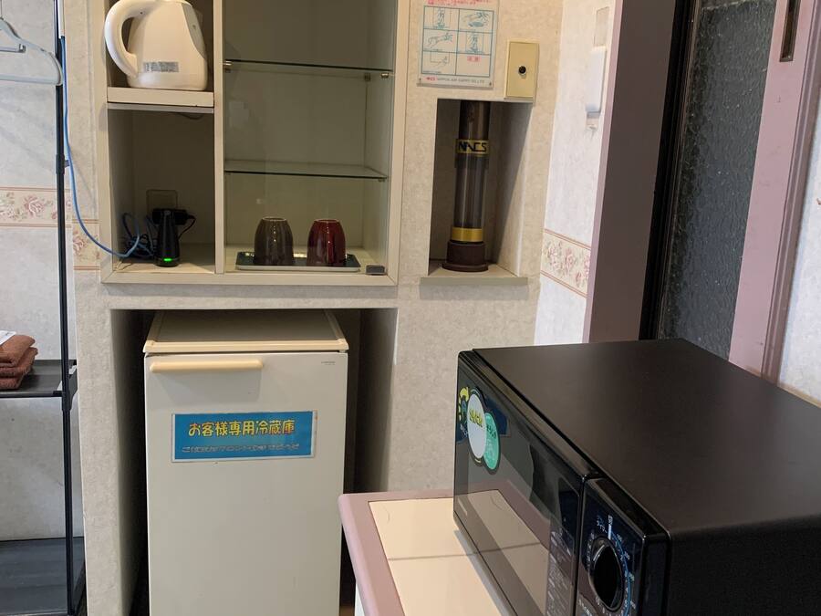 Une chambre d’hôtel équipée d’un mini-bar, d’un réfrigérateur, d’un four à micro-ondes et d’un petit meuble contenant une bouilloire et des tasses.
