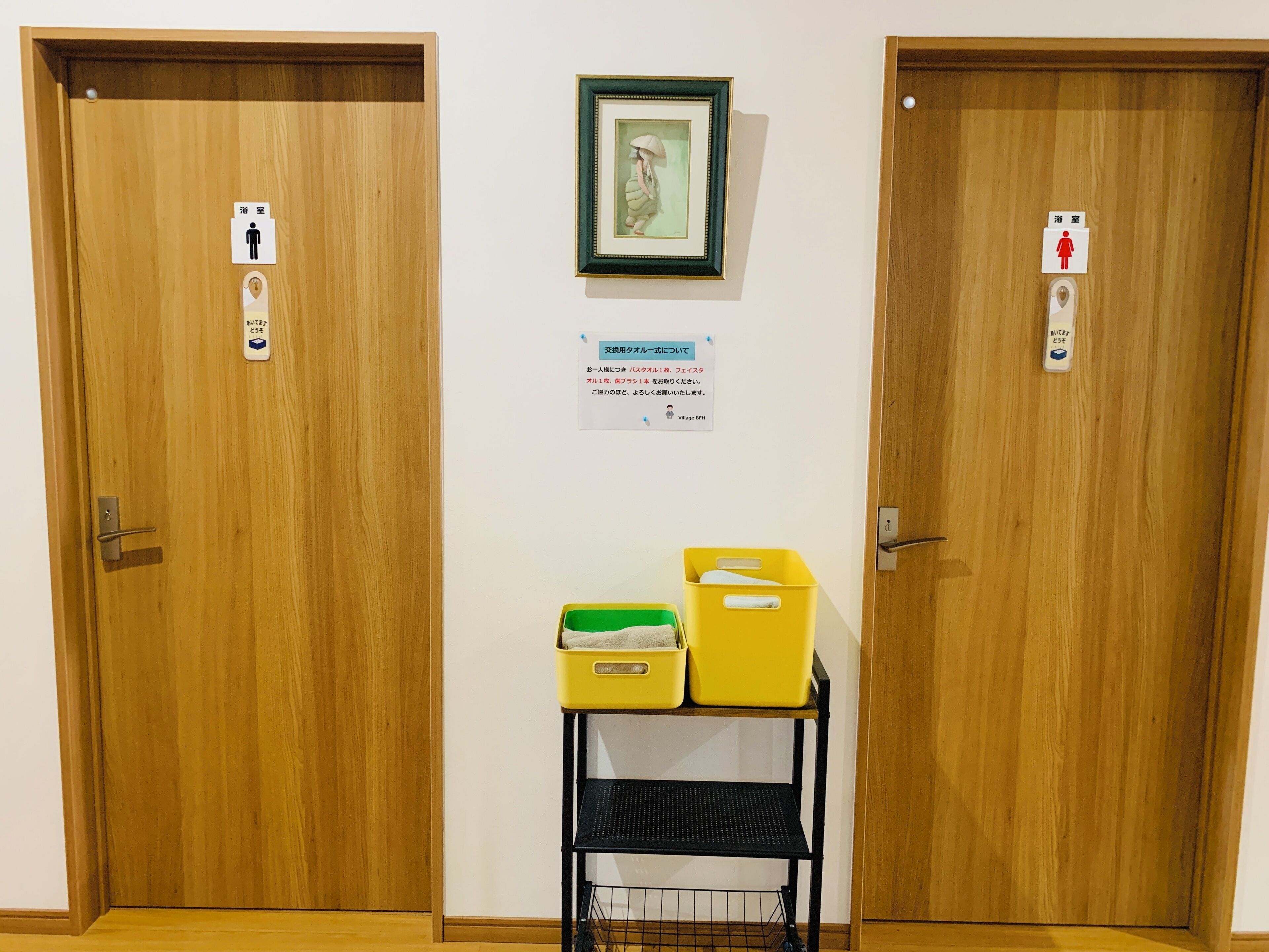 Twee houten deuren met tekens voor mannen en vrouwen, een lijst met een foto en een bericht over het gebruik van het toilet.