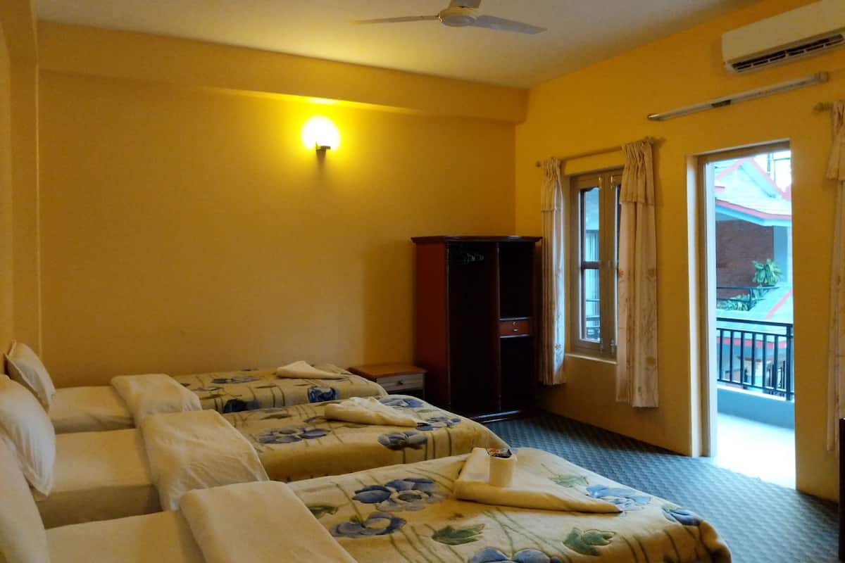 Habitación de hotel con dos camas, ventilador de techo, mesita de noche, armario y ventana con cortinas.