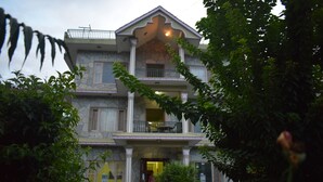 Una casa de dos pisos con un balcón, un porche y una escalera que lleva a la entrada.