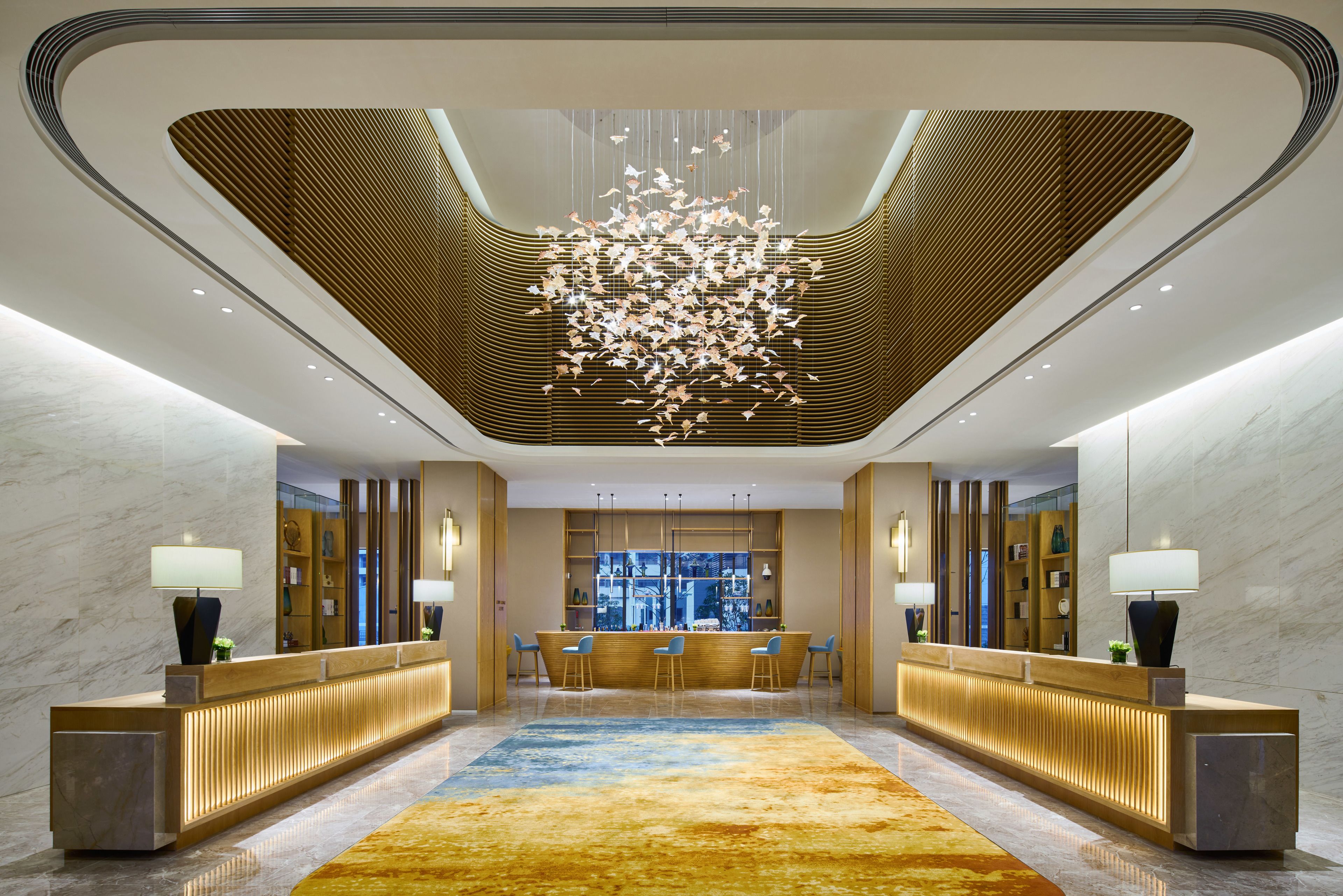 Eine moderne Hotelhalle mit Empfangstresen, Bar und Sitzgelegenheiten.
