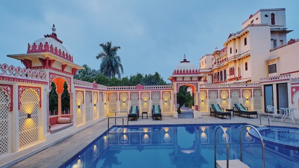A swimming pool with lounge chairs and a decorative fence. - Fort Dhariyawad Heritage Hotel Udaipur (Dhariyawad)
