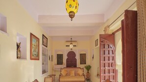 A traditional living room with a sofa, two chairs, a coffee table, and a decorative ceiling light. - Fort Dhariyawad Heritage Hotel Udaipur (Dhariyawad)