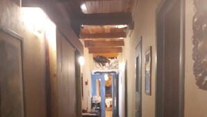 Un pasillo estrecho con pisos y paredes de madera, que conduce a una habitación con una mesa y sillas.