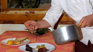 Un chef preparando comida en una cocina con vista a árboles.