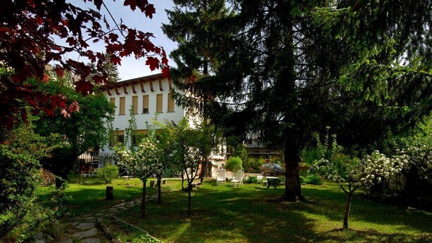 Un patio con un edificio al fondo, rodeado de árboles y un sendero de piedra.