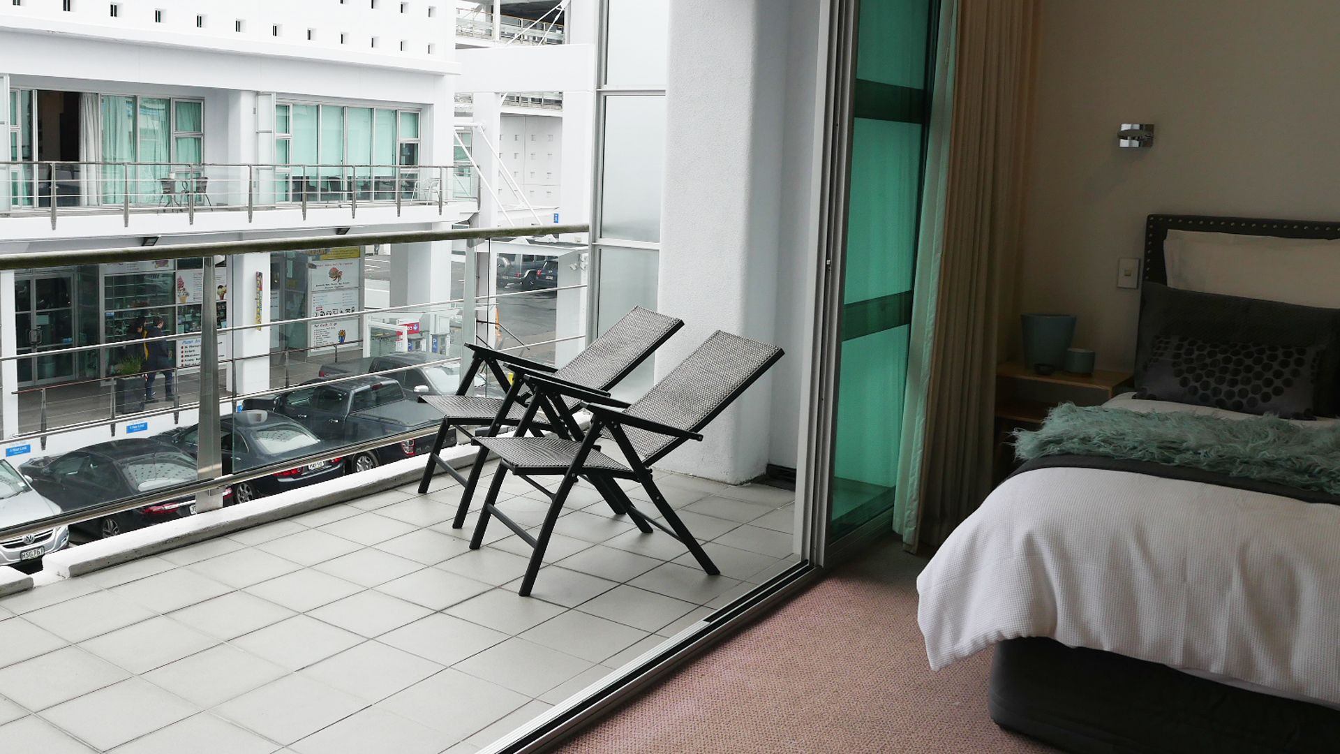 Habitación de hotel con balcón, cama y vista a la calle.