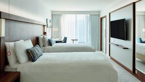 Ein Hotelzimmer mit zwei Betten, einem Fernseher, einem Schreibtisch und einem Stuhl.